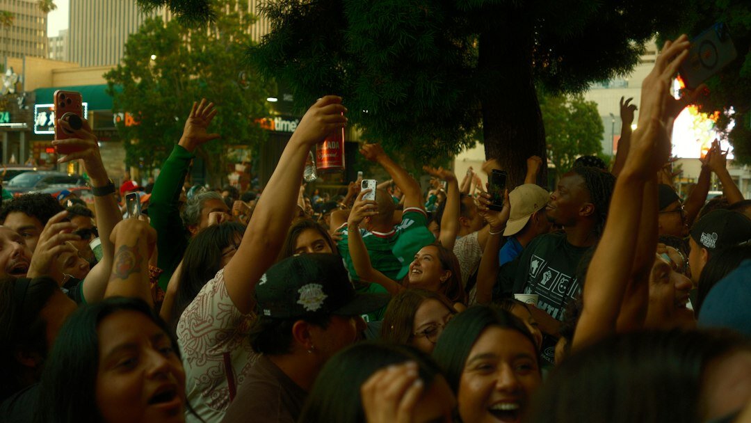 Diverse Mexican team celebrating with hands raised outdoors
